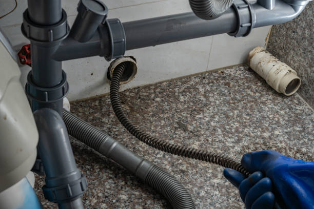 plumber using equipment to remove grease from the drain pipe